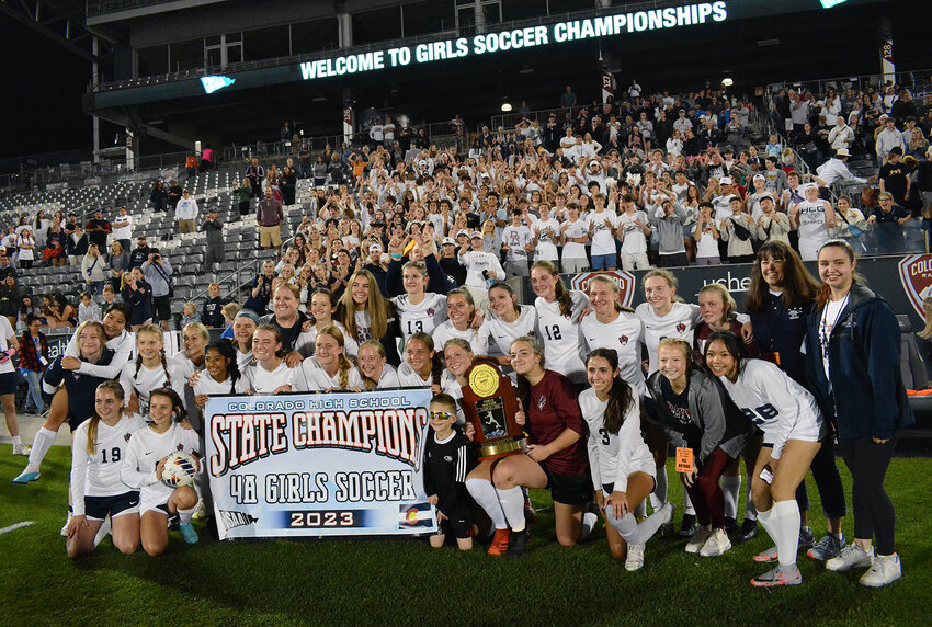 Dakota Ridge's girls soccer team pose with the state title with the Eagles' student section in the background after the Eagles' 2-0 victory over Lutheran on May 23 at Dick's Sporting Goods Park.